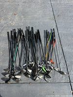 Full group of approximately 26 golf clubs laid out on pavement