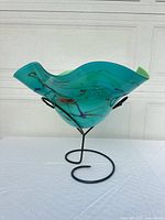 Side view of teal art glass bowl on wrought-iron stand