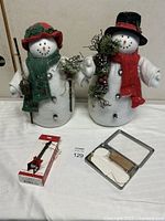 Full lot view showing both snowmen, boxed guitar ornament and folding stand