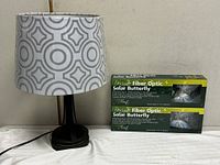 Table lamp beside two boxes of Designer Fiber Optic Solar Butterfly lights