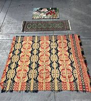 All three textiles laid out: square woven rug, runner rug, floral tapestry