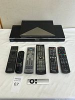 Both Blu-ray players stacked with seven of the remotes laid out below