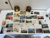 Full layout of both clocks, coin box and spread of postcards and ephemera on table