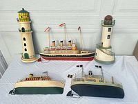 Five metal wall hangings: three ships, two lighthouses displayed together