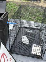 large Precision wire dog crate with tray, Toyota sign, portion of trash bin