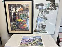 Group shot of all three prints: two framed standing, one loose on table