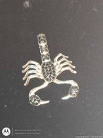 Front view of sterling silver scorpion pendant showing black stones