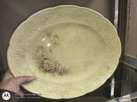 Front view of oval platter showing embossed rim and central floral/tree motif