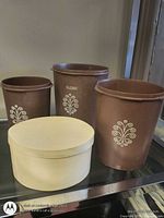 front view three brown canisters and oval wood box