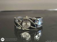 Front view of silver-tone cuff bracelet watch showing dial and band design