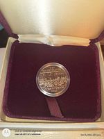 Coin in capsule seated in burgundy velvet interior of presentation box
