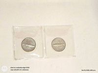 Both coins reverse side showing mackerel design in plastic flip