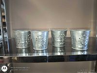 Front view of four galvanized perforated pail candle holders