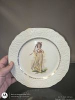 Front of plate showing girl motif, embossed rim and overall condition
