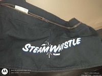 Close-up of Steam Whistle logo and zipper on black apron