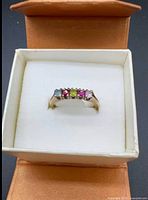 Ring in open gift box showing multi-coloured gemstones
