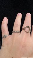 Three rings on hand showing plain band, patterned band, bezel mounting