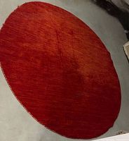 Full view of round red/orange wool rug on floor