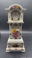 Full front view of porcelain clock showing overall form and floral decoration