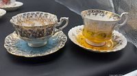 Two Royal Albert teacup and saucer sets displayed on black backdrop