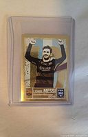 Front view of gold sticker showing Lionel Messi in Barcelona kit within protective sleeve