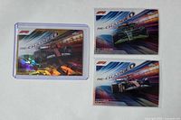 Three trading cards laid out: gold parallel Carlos Sainz in top loader, Valtteri Bottas insert, Charles Leclerc insert
