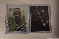Fronts of both Lionel Messi trading cards in sleeves