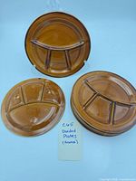 Stack of six brown divided plates plus two plates displayed, underside stamp visible