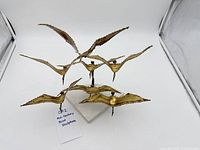 Front view of six-bird metal sculpture on white base