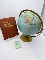 Full view of globe on stand beside atlas