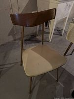 Full view of chair showing metal frame, faux wood back, vinyl seat