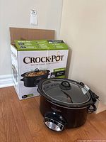 Slow cooker in front of retail box showing brand and series