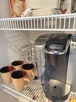 Front view of Keurig brewer with mugs and carousel visible