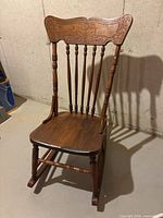 Front angle view showing carved backrest, seat, spindles, rockers