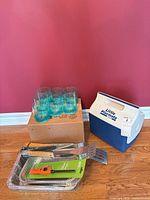 Group shot: cooler, box of tumblers, BBQ tools, lighter, foil trays