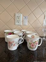 Six assorted floral bone china mugs on countertop