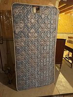 Full view of twin mattress standing upright in basement