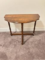 Full view of demi-lune console table showing three turned legs and stretcher