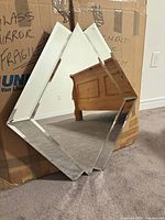 Front view of diamond-shaped beveled mirror leaning against box