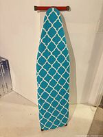 Ironing board front with teal quatrefoil cover visible