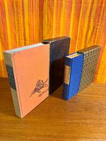 Both books with their slipcases standing upright on table