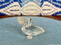 Side view of clear crystal pelican figurine on blue background