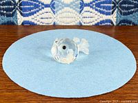 Front view of faceted crystal pufferfish with frosted fins on blue circle