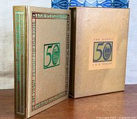 Front view of book and slipcase showing 50th anniversary emblem and gilt design