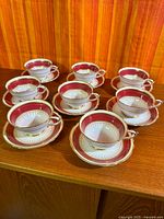 Eight cup and saucer pairs arranged on wooden surface