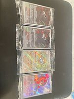 Four sleeved Pokémon cards laid out showing two identical Zarude, one Magneton, one Charcadet