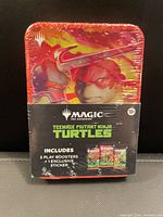 Front view of sealed TMNT MTG collector tin showing artwork and contents list