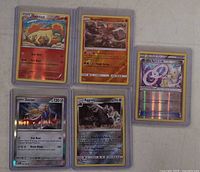 Front view of all five Pokémon cards in top loaders