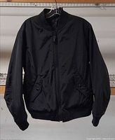 Front view of black Coach bomber jacket hanging
