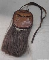 Front view of leather sporran showing flap, pouch, adjustable strap and horsehair tassels